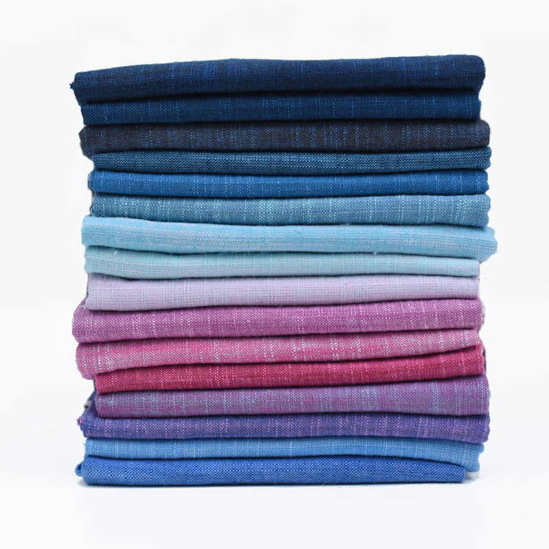 Stack of folded fabric swatches in various blue and pink colors on a white background