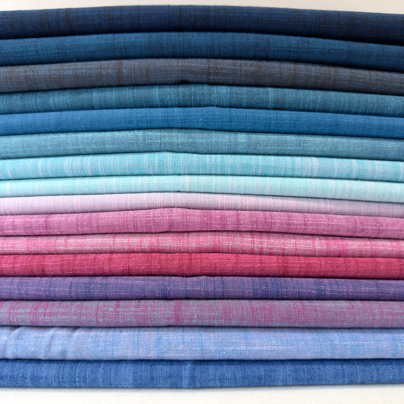 Stack of folded fabric swatches in various blue and pink shades.