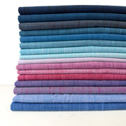 Stack of folded fabric swatches in various blue and pink shades on a white background