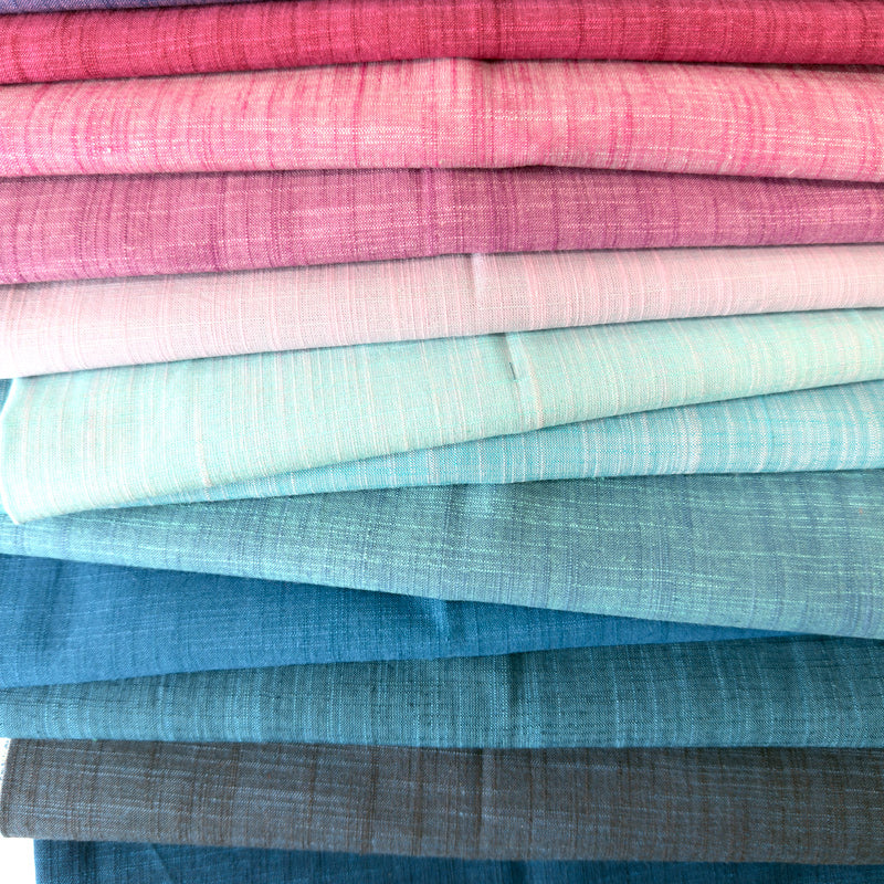 Stack of folded fabric swatches in pink, blue, and gray.