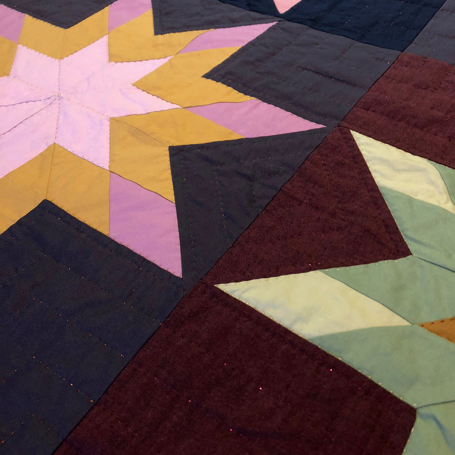 Close-up of a colorful quilt with metallic hand quilting