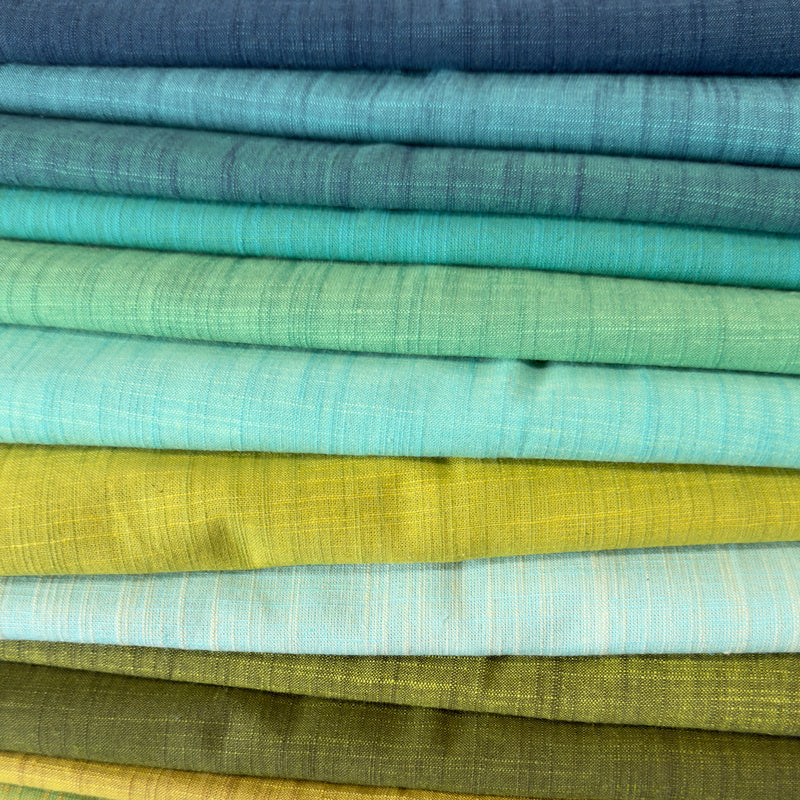 Stack of fabric swatches in various shades of blue, green, and yellow.