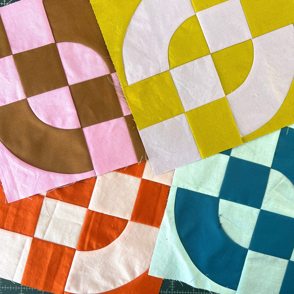 Quilt blocks in a pile, in multiple colors, made of 4 patches and drunkards path blocks