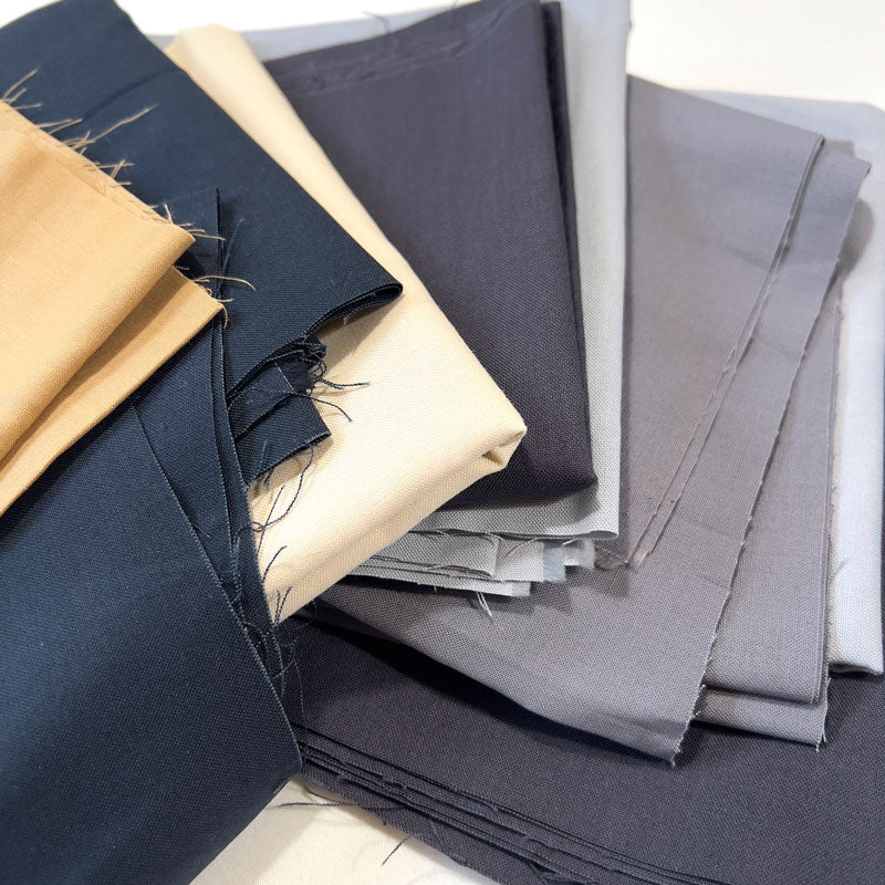 Stack of folded fabric sheets in various colors on a white background