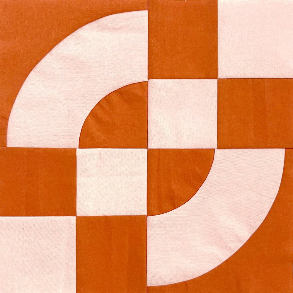 A single quilt block, in pink and rust colors, made of 4 patches and drunkards path blocks