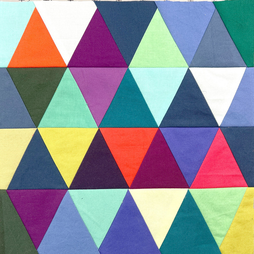 Small quilt block in bright colors, made up of rows of triangles