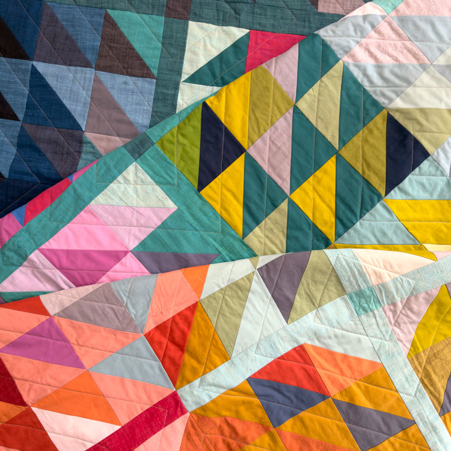 Colorful geometric quilt with triangular patterns showing machine quilting.