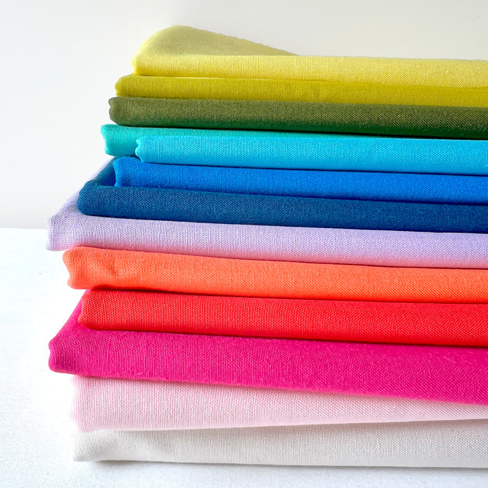 A rainbow colored pile of quilting cottons.
