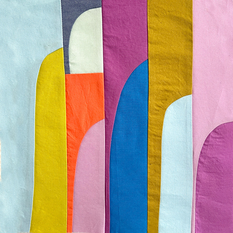 Small textile art made of tall, curved drunkard's path blocks in bright and pastel tone colors 
