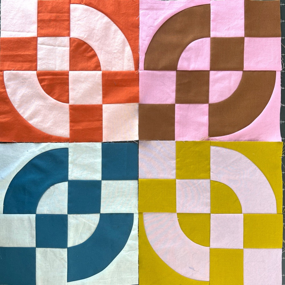 Quilt blocks in a pile, in multiple colors, made of 4 patches and drunkards path blocks