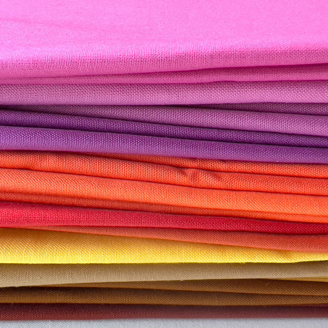 Stack of colorful fabric swatches in a rainbow pattern on a white background