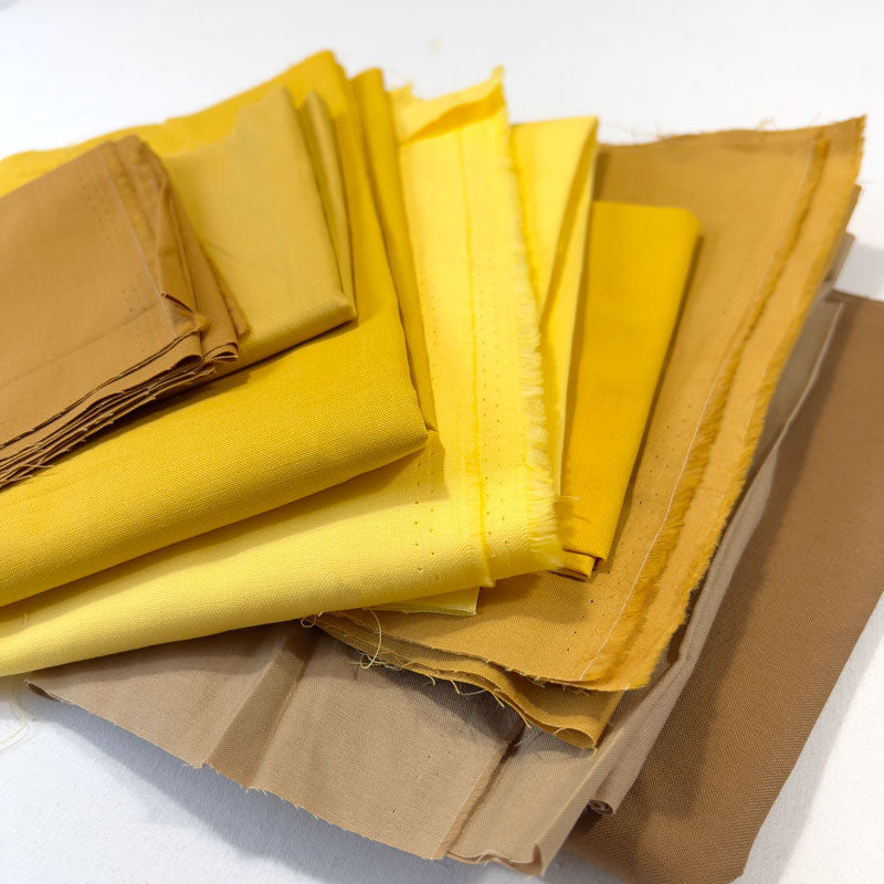 Stack of yellow and brown fabric swatches on a white background