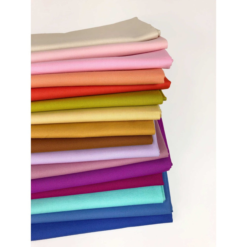 a stack of quilting fabrics in a rainbow of colors