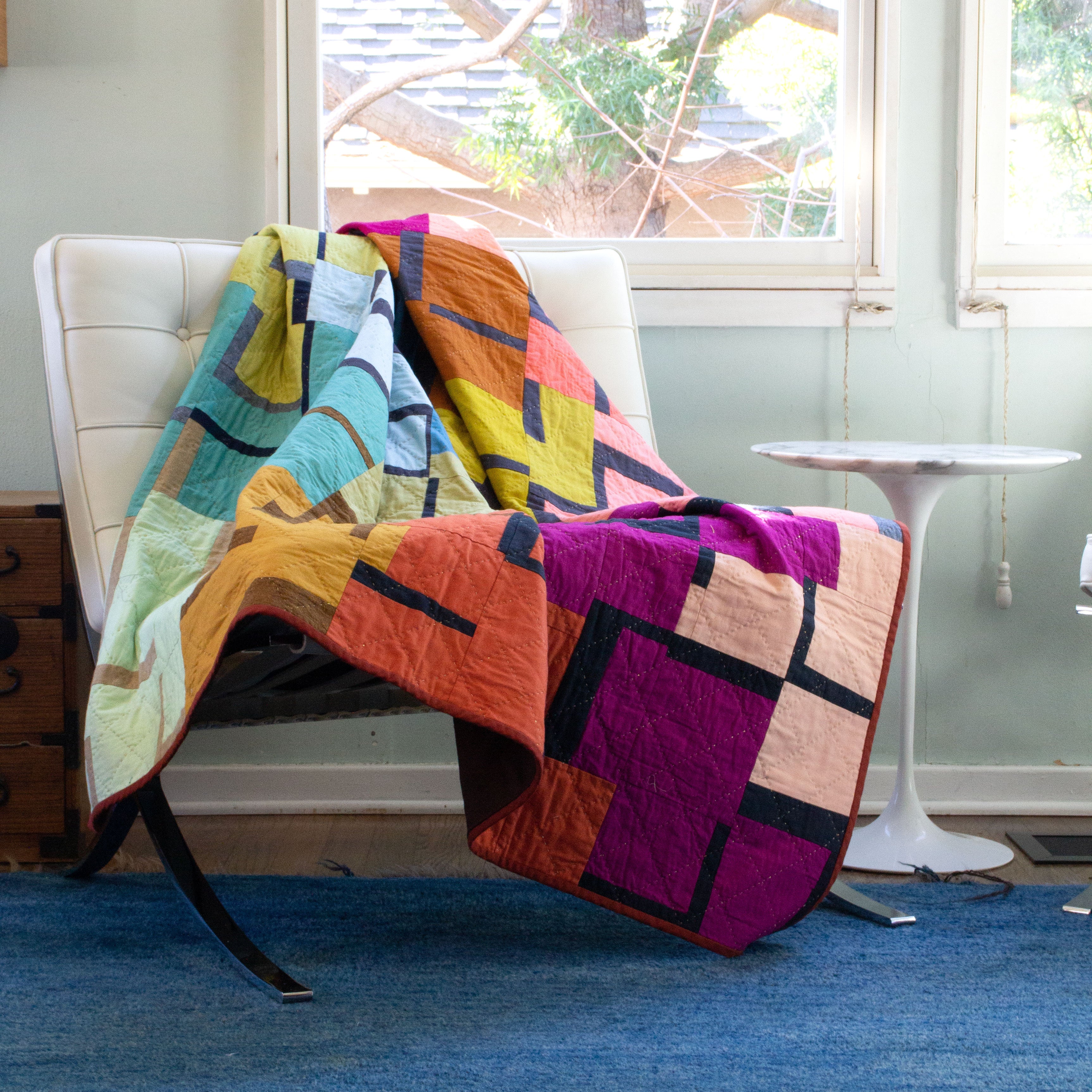 Image of quilt on a bench next to a small table