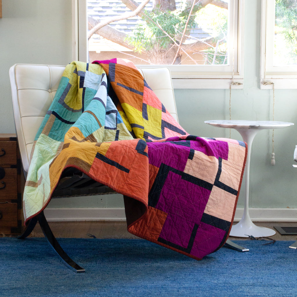 Image of quilt on a bench next to a small table